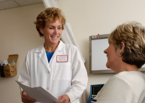 Female doctor in a white coat talking with a patient in an exam room